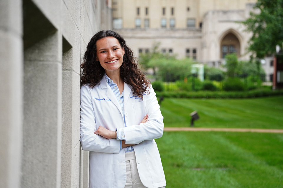 McKenna Smith A student wearing a white doctor's coat poses for a photo outside on campus.