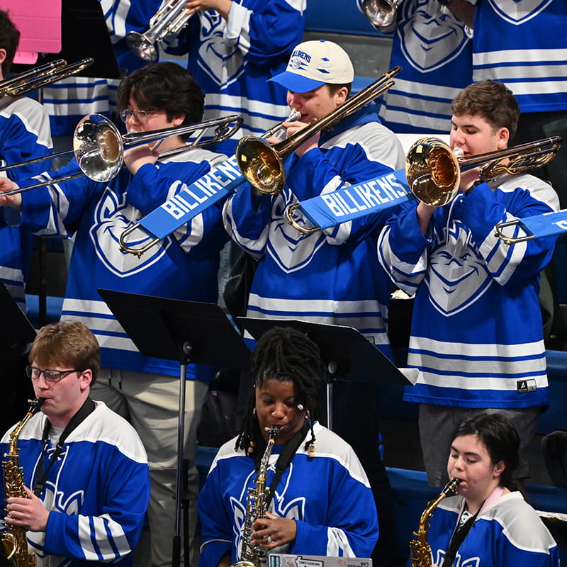 Students wearing Billiken shirts play trombones and saxophones.