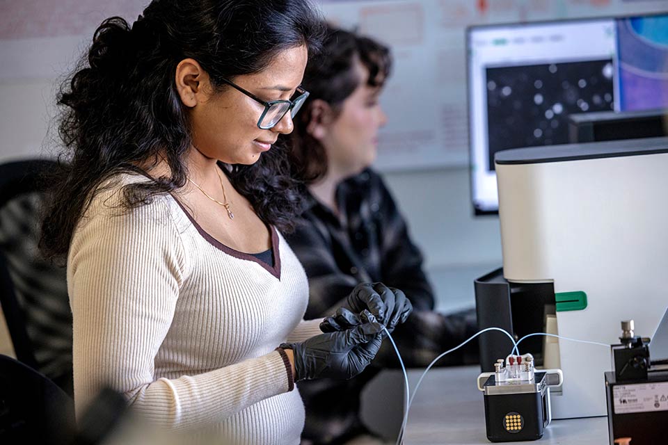 Student and faculty member using machine in lab