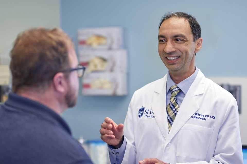 An endocrinologist speaks with his patient inside a hospital exam room.