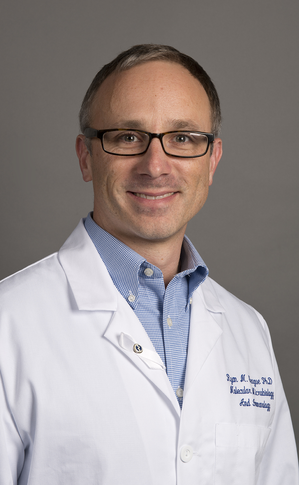 A photo of Dr. Ryan Teague wearing a white lab coat.